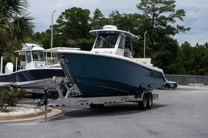 Slide: The Image of 2026 Solace 30 CS boat on trailer, parked outdoors with trees in background. - 3