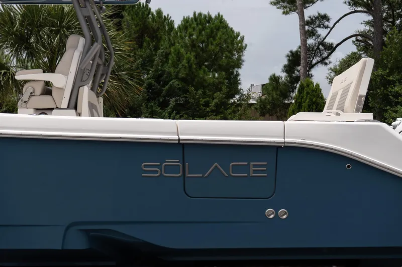 Slide: The Image of 2026 Solace 30 CS boat side view with seating, set against a lush green background. - 9