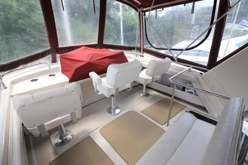 Slide: The Image of 1990 Silverton 40 Aft Cabin interior with white seating and red cover, enclosed by windows. - 11