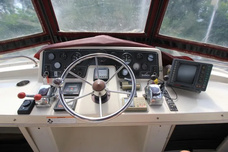 Slide: The Image of 1990 Silverton 40 Aft Cabin helm with steering wheel, gauges, and navigation equipment. - 12