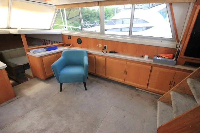 Slide: The Image of 1990 Silverton 40 Aft Cabin interior with blue chair, wooden cabinets, and large windows. - 18