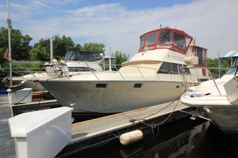 Slide: The Image of 1990 Silverton 40 Aft Cabin yacht docked at marina under blue sky. - 2