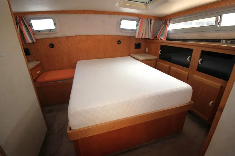 Slide: The Image of 1990 Silverton 40 Aft Cabin bedroom with bed, wood paneling, and storage cabinets. - 21