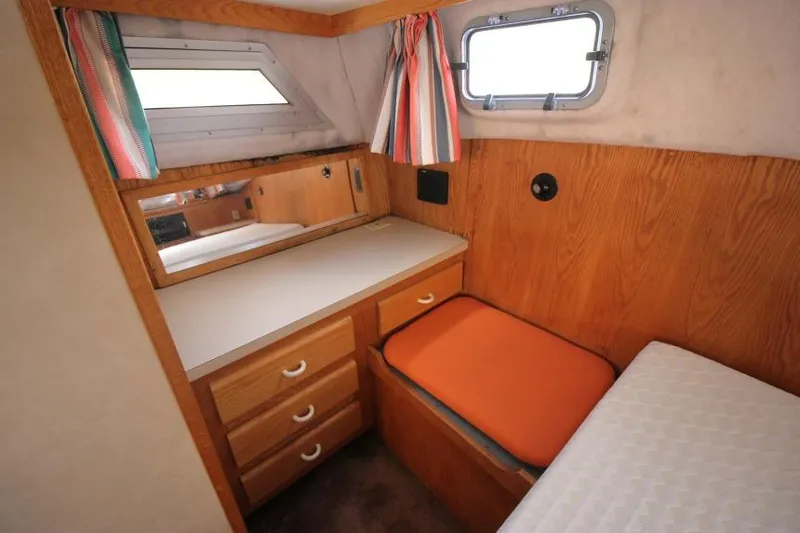 Slide: The Image of 1990 Silverton 40 Aft Cabin interior with wood cabinetry, orange cushion, and striped curtains. - 22