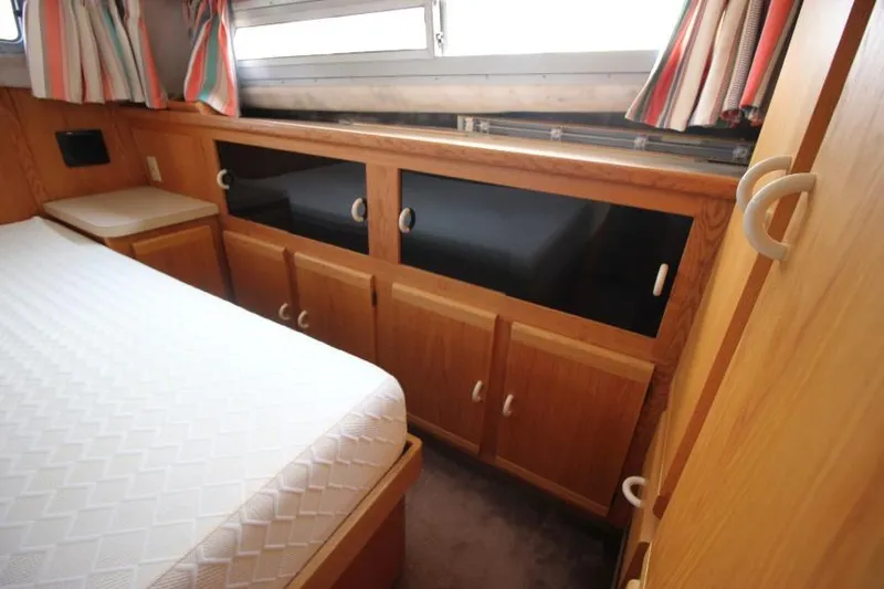 Slide: The Image of 1990 Silverton 40 Aft Cabin interior with wood cabinetry and bed, featuring colorful curtains. - 23