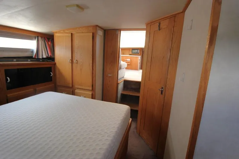 Slide: The Image of 1990 Silverton 40 Aft Cabin interior with bed, wooden cabinets, and natural light. - 24