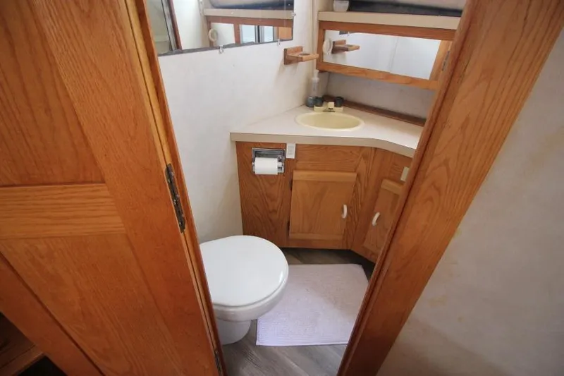 Slide: The Image of 1990 Silverton 40 Aft Cabin bathroom with wooden cabinets and white fixtures. - 26