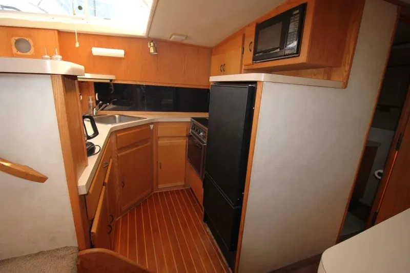 Slide: The Image of 1990 Silverton 40 Aft Cabin kitchen with wood cabinetry, appliances, and compact design. - 30