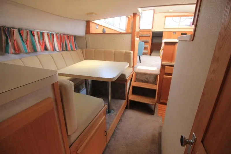 Slide: The Image of 1990 Silverton 40 Aft Cabin interior with dining area, beige seating, and colorful curtains. - 34