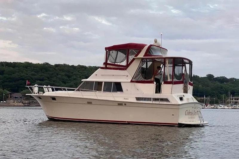 Slide: The Image of 1990 Silverton 40 Aft Cabin yacht on calm water, featuring a red canopy. - 36