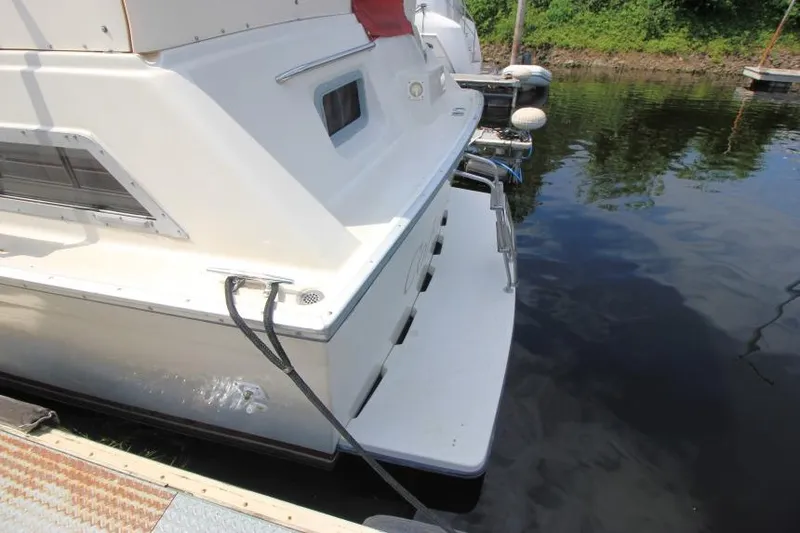 Slide: The Image of 1990 Silverton 40 Aft Cabin boat docked, showing rear deck and water reflection. - 4