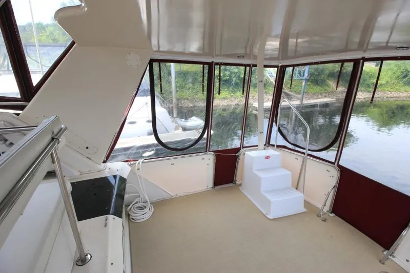 Slide: The Image of 1990 Silverton 40 Aft Cabin interior with large windows and white steps, docked by a serene river. - 7