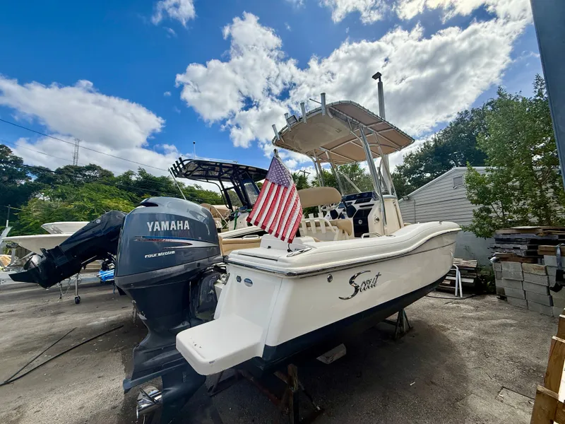 Slide: The Image of 2012 Scout 210 XSF boat with Yamaha engine and American flag, parked outdoors. - 1