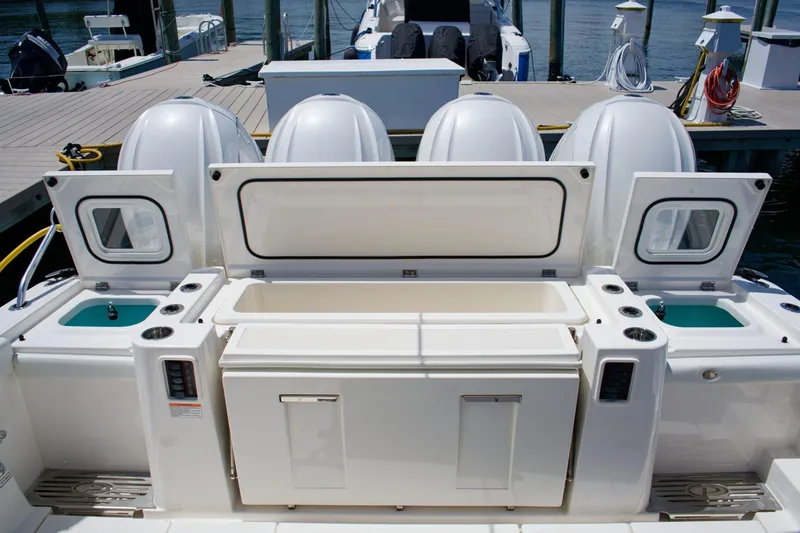 Slide: The Image of 2022 Pursuit S 428 Sport boat with open storage compartments and four engines at dock. - 24