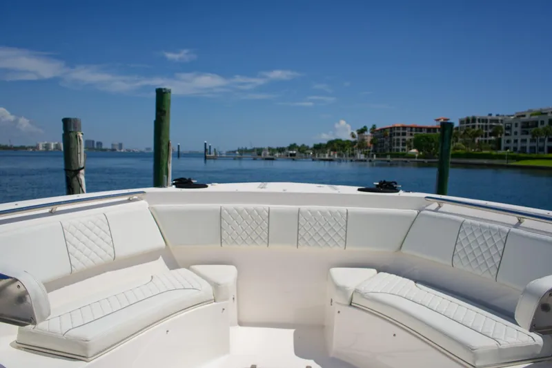 Slide: The Image of 2022 Pursuit S 428 Sport boat interior with white seating, docked by waterfront homes. - 4