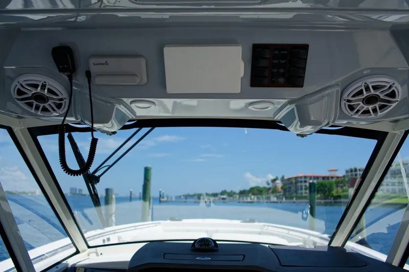 Slide: The Image of 2022 Pursuit S 428 Sport boat interior with speakers and navigation equipment, overlooking marina. - 7