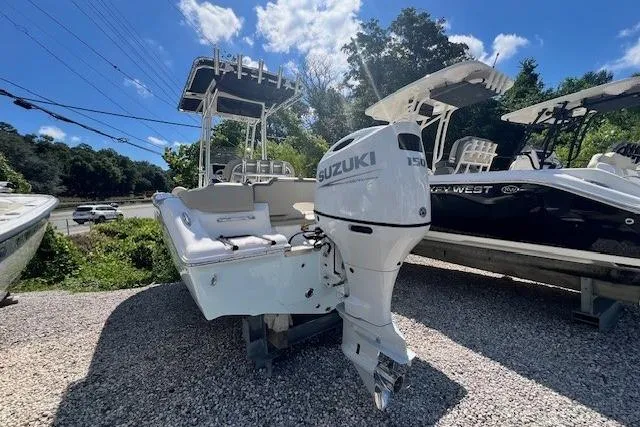 Slide: The Image of 2025 Key West 203 FS boat with Suzuki engine, parked on gravel under a sunny sky. - 1