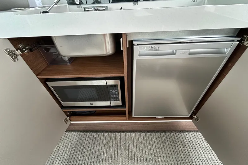 Slide: The Image of 2024 Beneteau Antares 11 kitchen with microwave and compact refrigerator. - 19