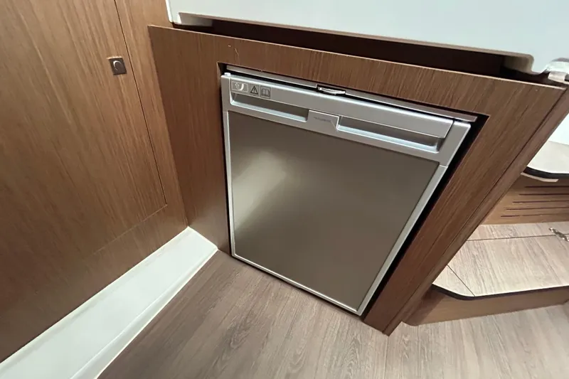 Slide: The Image of Compact refrigerator in 2024 Beneteau Antares 11 boat interior, featuring sleek wood paneling. - 23