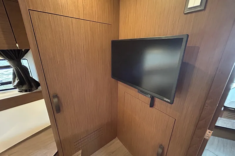 Slide: The Image of 2024 Beneteau Antares 11 interior with mounted TV and wooden cabinetry. - 25