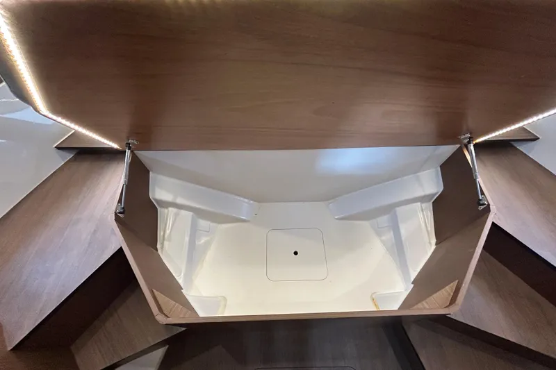 Slide: The Image of 2024 Beneteau Antares 11 interior storage compartment with wooden finish and LED lighting. - 28
