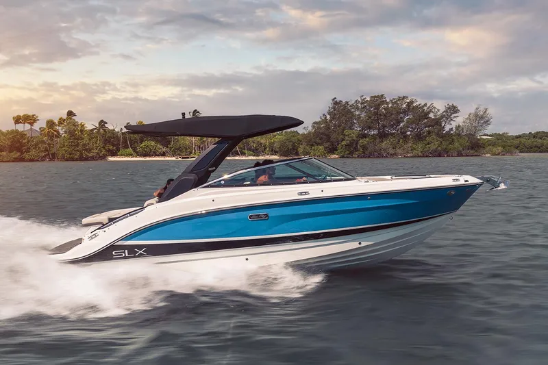 Slide: The Image of Manufacturer Provided Image: 2023 Sea Ray SLX 260 boat cruising on water near a tropical shoreline. - 29