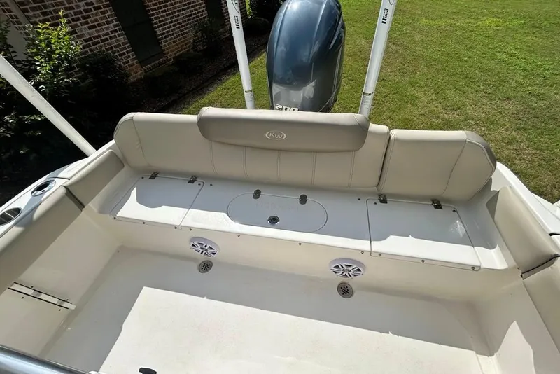 Slide: The Image of 2022 Key West 219 FS boat interior with seating and motor, parked on grass. - 15
