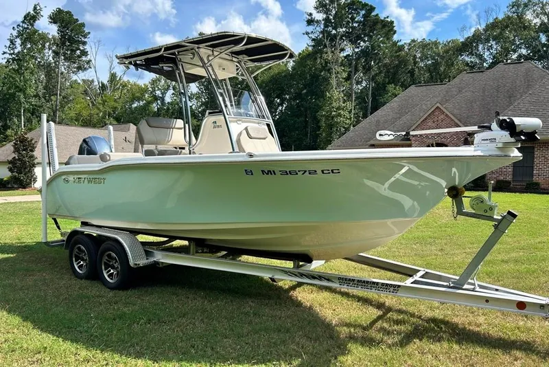 Slide: The Image of 2022 Key West 219 FS boat on trailer, parked on grass, with trees and houses in background. - 42