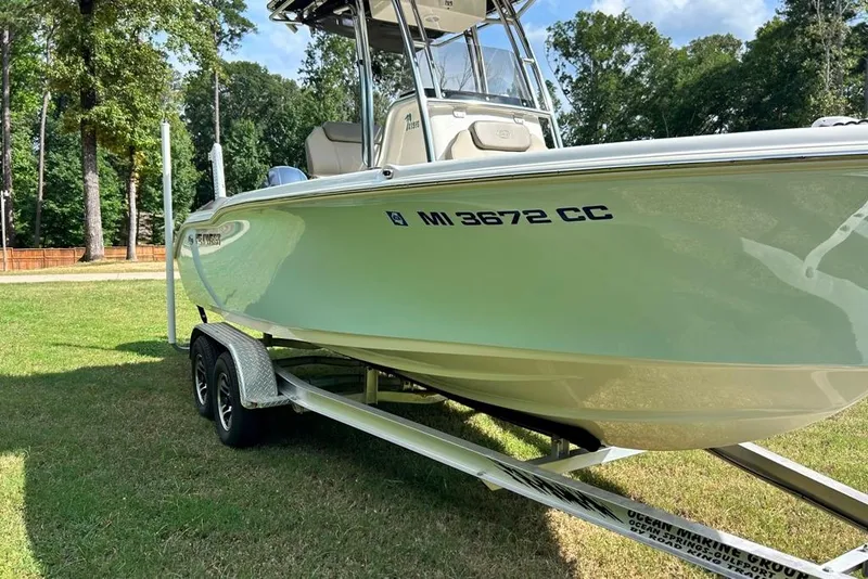 Slide: The Image of 2022 Key West 219 FS boat on trailer, parked on grass with trees in background. - 43