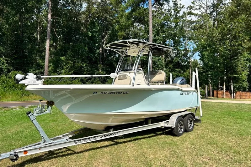Slide: The Image of 2022 Key West 219 FS boat on trailer, parked on grass with forest background. - 46