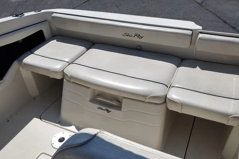 Slide: The Image of 1999 Sea Ray 215 Express Cruiser interior seating, featuring white cushioned benches. - 27