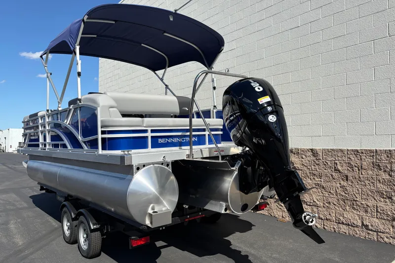 Slide: The Image of 2026 Bennington 21 SSB pontoon boat with outboard motor and canopy, parked on trailer. - 2
