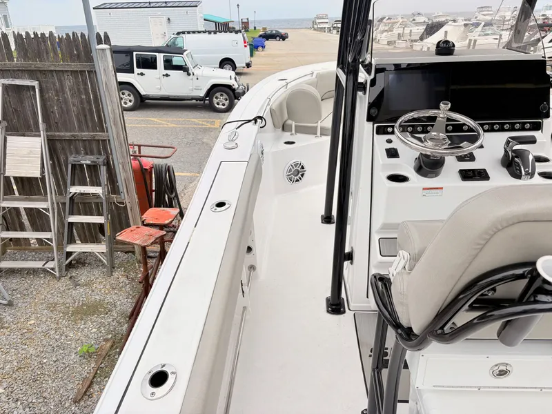 Slide: The Image of 2022 Sportsman 241 Heritage boat interior with steering console and seating, parked near vehicles. - 14