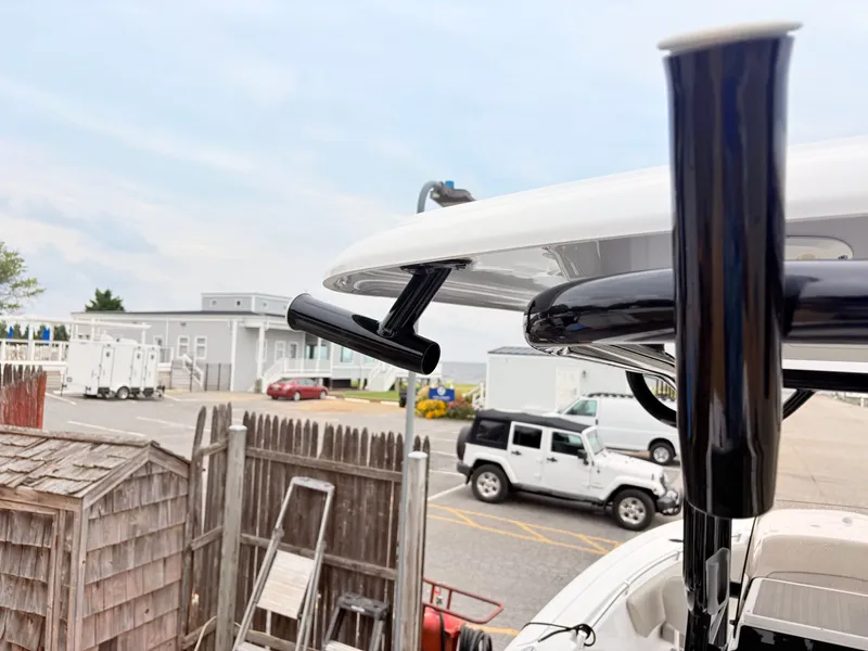 Slide: The Image of 2022 Sportsman 241 Heritage boat detail with rod holders, parked vehicles in background. - 24