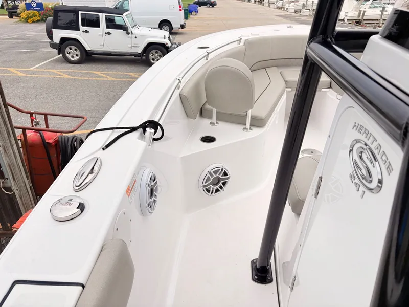 Slide: The Image of 2022 Sportsman 241 Heritage boat interior with seating and speakers, parked near vehicles. - 25