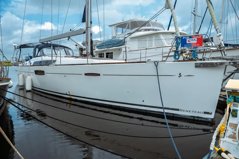 The Image of 2016 Beneteau Oceanis 60 yacht docked, for sale, with clear skies and calm waters. - 0
