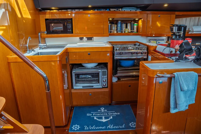 Slide: The Image of Luxurious 2016 Beneteau Oceanis 60 yacht kitchen with modern appliances and wooden cabinetry. - 24
