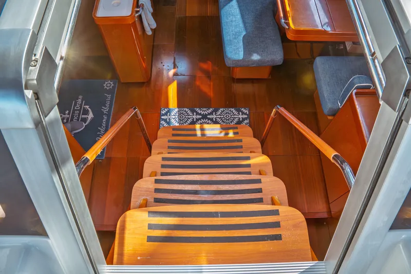 Slide: The Image of Interior view of 2016 Beneteau Oceanis 60 yacht, featuring wooden stairs and cozy seating area. - 33