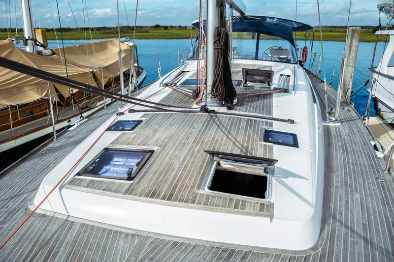 Slide: The Image of 2016 Beneteau Oceanis 60 sailboat deck with open hatches, docked by calm waters. - 48
