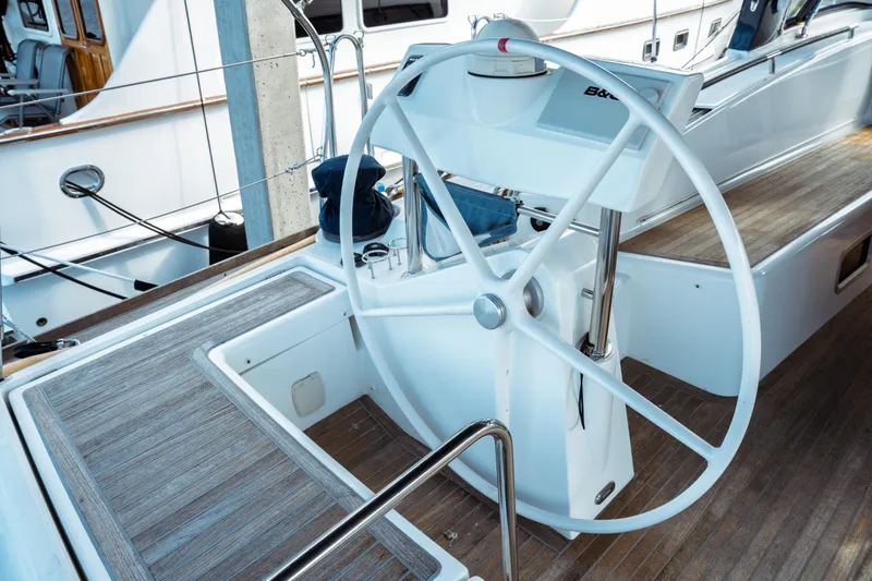 Slide: The Image of Steering wheel of a 2016 Beneteau Oceanis 60 yacht, featuring sleek design and wooden deck. - 52