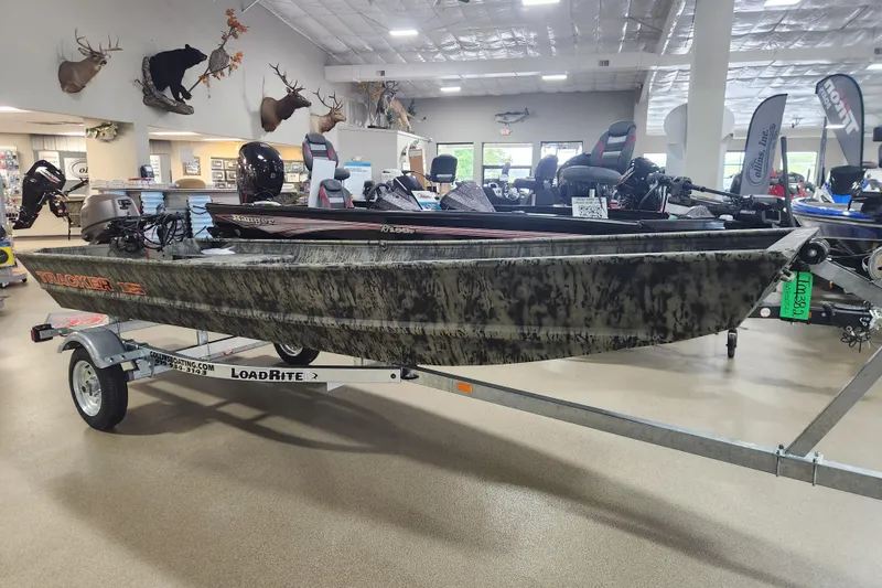 Slide: The Image of 2026 Tracker 1542 LW boat on LoadRite trailer in showroom with mounted motors. - 2