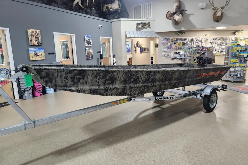 Slide: The Image of 2026 Tracker 1542 LW boat on Load Rite trailer in showroom with hunting decor. - 4