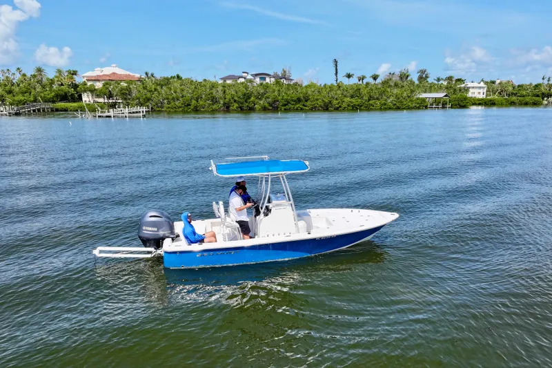 Slide: The Image of 2016 Sea Hunt BX 20 BR boat cruising on a sunny day, with lush greenery in the background. - 8