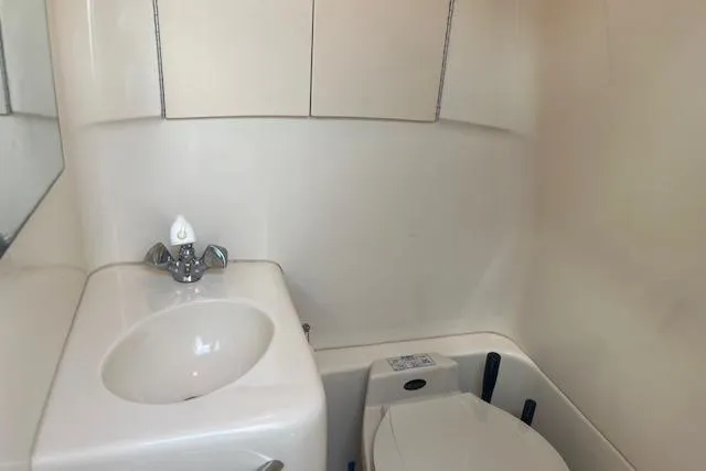 Slide: The Image of Compact bathroom in a 2000 Sea Ray 270 Sundancer boat, featuring a sink and toilet. - 12