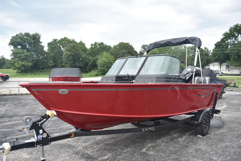 Slide: The Image of 2026 Lund 1775 Adventure Sport boat in vibrant red on a trailer, parked outdoors. - 3