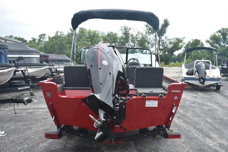 Slide: The Image of 2026 Lund 1775 Adventure Sport boat, red exterior, rear view with motor, parked outdoors. - 4
