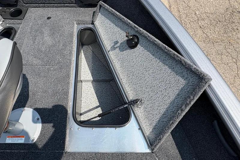 Slide: The Image of 2026 Lund 1875 Impact XS Sport boat storage compartment open, revealing interior space. - 13