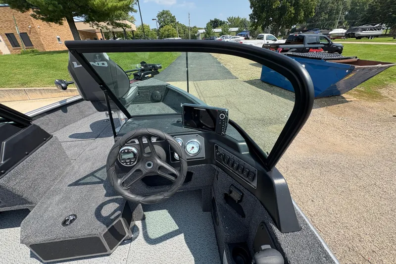 Slide: The Image of 2026 Lund 1875 Impact XS Sport boat interior with steering wheel and dashboard controls. - 20