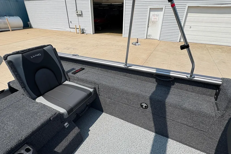 Slide: The Image of 2026 Lund 1875 Impact XS Sport boat interior with gray seating and carpeted flooring. - 24