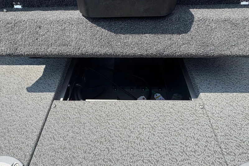 Slide: The Image of 2026 Lund 1875 Impact XS Sport boat interior storage compartment with gray carpet. - 33
